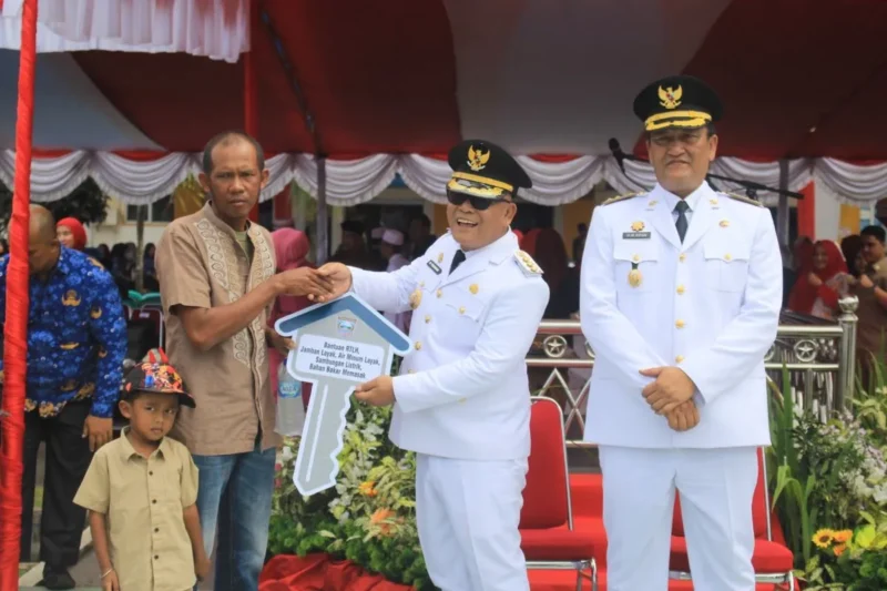 Bupati Pasbar Yulianto menyerahkan bantuan CSR perusahaan sawit kepada keluarga penerima manfaat, Minggu (17/8/2025). (Foto: Diskominfo Pasbar)