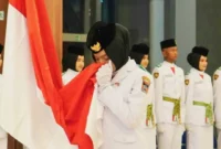 Momen Viersha Aura Fania mencium Bendera Merah Putih saat  pengukuhan anggota Paskibraka Padang di Gedung Youth Center, Jumat (15/8/2025). (Foto: Diskominfo Padang)