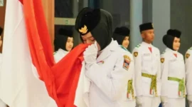 Momen Viersha Aura Fania mencium Bendera Merah Putih saat  pengukuhan anggota Paskibraka Padang di Gedung Youth Center, Jumat (15/8/2025). (Foto: Diskominfo Padang)