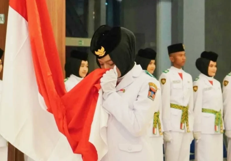 Momen Viersha Aura Fania mencium Bendera Merah Putih saat  pengukuhan anggota Paskibraka Padang di Gedung Youth Center, Jumat (15/8/2025). (Foto: Diskominfo Padang)