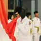Momen Viersha Aura Fania mencium Bendera Merah Putih saat  pengukuhan anggota Paskibraka Padang di Gedung Youth Center, Jumat (15/8/2025). (Foto: Diskominfo Padang)
