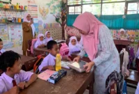 Ketua TP-PKK Ny. Sifrowati Yulianto membagikan makanan bergizi kepada siswa SDN 05 Pasaman. (Foto: Diskominfo Pasbar)