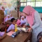 Ketua TP-PKK Ny. Sifrowati Yulianto membagikan makanan bergizi kepada siswa SDN 05 Pasaman. (Foto: Diskominfo Pasbar)