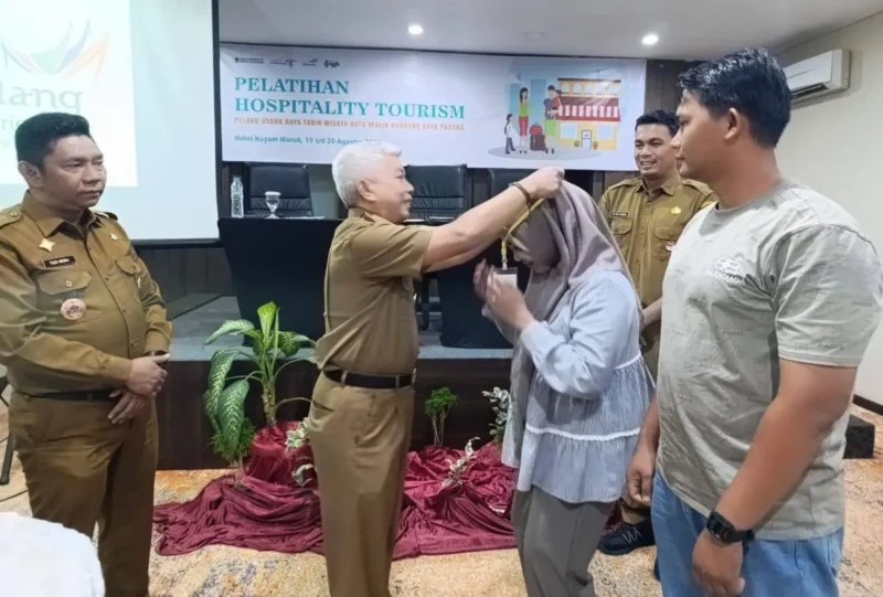 Staf Ahli Wali Kota Padang Bidang SDM dan Kemasyarakatan, Syahrial Kamat memasangkan kokarde kepada peserta Pelatihan Hospitality Tourism, Selasa (19/8/2025). (Foto: FB Diskominfo Padang)