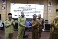 Wako Padang Fadly Amran menyerahkan kenang-kenangan kepada Kepala Bapenda Yosefriawan yang memasuki masa purna bakti di sela-sela rapat bulanan, Senin (22/9/2025). (Foto: Prokopim Padang)