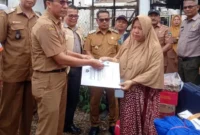Kepala Dinas Dukcapil Pessel, Beriskhan disaksikan Wabup Pessel, Risnaldi Ibrahim menyerahkan dokumen kependudukan kepada korban kebakaran di Nagari Koto VIII Palangai. (Foto: Dok. Yoniks)