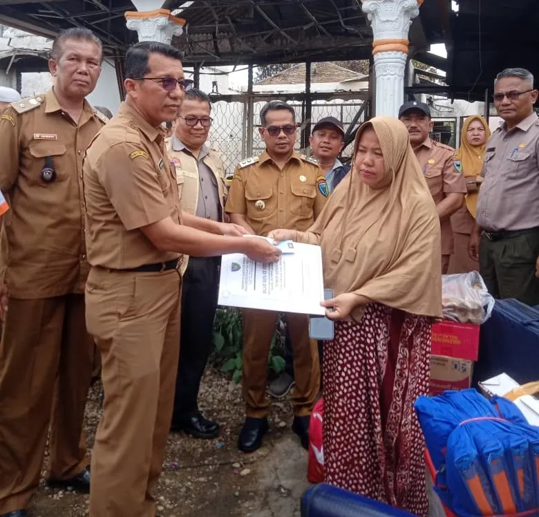 Kepala Dinas Dukcapil Pessel, Beriskhan disaksikan Wabup Pessel, Risnaldi Ibrahim menyerahkan dokumen kependudukan kepada korban kebakaran di Nagari Koto VIII Palangai. (Foto: Dok. Yoniks)