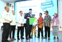 Wali Kota Padang, Fadly Amran menyerahkan secara simbolis menyerahkan Kartu BPJS Ketenagakerjaan kepada.000 pekerja rentan di Gedung Bagindo Aziz Chan Youth Center, Selasa (28/10/2025). (Foto: Prokopim Padang)