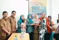 Ketua TP-PKK sekaligus Ketua TP Posyandu Kabupaten Solsel, Ny. Hj. Erniati Khairunas menyerahkan bantuan kepada warga. (Foto: Humas Pemkab Solsel)