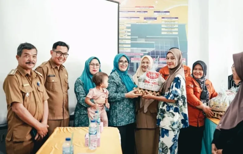 Ketua TP-PKK sekaligus Ketua TP Posyandu Kabupaten Solsel, Ny. Hj. Erniati Khairunas menyerahkan bantuan kepada warga. (Foto: Humas Pemkab Solsel)