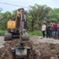 Operator alat berat melakukan penggalian parit di badan jalan untuk memblokir akses kendaraan menuju perusahaan. (Foto: Dok. OKM)