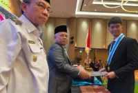 Kepala SMK SMAK Padang Nasir menyerahkan ijazah kepada lulusan saat prosesi pelantikan angkatan ke-57 di The ZHM Premiere Hotel Padang, Rabu (8/10/2025). Hadir menyaksikan Wawako Padang Maigus Nasir. (Foto: Humas SMK SMAK Padang)