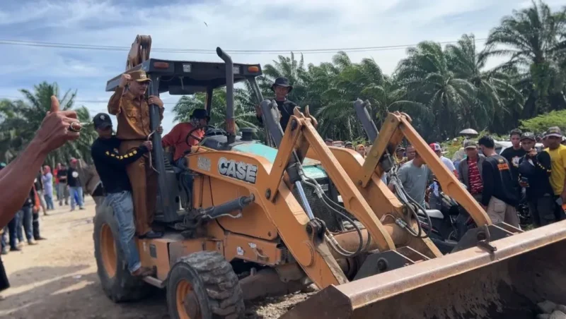 Bupati Pessel Hendrajoni menaiki ekskavator saat pembukaan akses jalan menuju PT Incasi Raya.