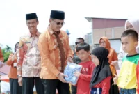 Bupati Solsel H. Khairunas didampingi Wakil Bupati H. Yulian Efi membagikan bantuan seragam gratis kepada siswa di RTH Padang Aro, Kamis (6/2025). (Foto: Humas Solsel)