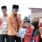 Bupati Solsel H. Khairunas didampingi Wakil Bupati H. Yulian Efi membagikan bantuan seragam gratis kepada siswa di RTH Padang Aro, Kamis (6/2025). (Foto: Humas Solsel)