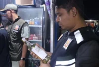 Kabid P3D Satpol PP Padang, Rio Ebu Pratama mengecek izi edar minuman berakohol di sebuah warung kawasan Jalan Veteran, Minggu (2/11/2025) dini hari. (Foto: Humas Satpol PP Padang)