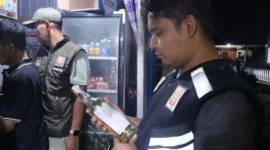 Kabid P3D Satpol PP Padang, Rio Ebu Pratama mengecek izi edar minuman berakohol di sebuah warung kawasan Jalan Veteran, Minggu (2/11/2025) dini hari. (Foto: Humas Satpol PP Padang)