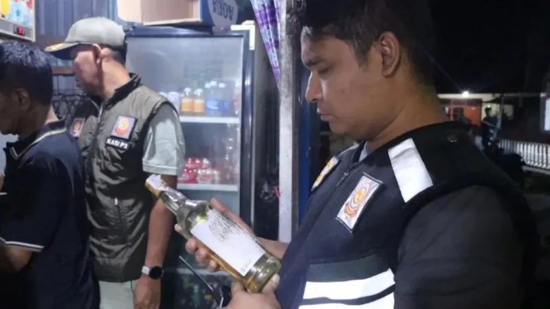Kabid P3D Satpol PP Padang, Rio Ebu Pratama mengecek izi edar minuman berakohol di sebuah warung kawasan Jalan Veteran, Minggu (2/11/2025) dini hari. (Foto: Humas Satpol PP Padang)
