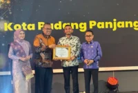 Sekdaprov Sumbar, Arry Yuswandi didampingi Ketua KI Sumbar, Musfi Yendra dan anggota Mona Sisca menyerahkan penghargaan kepada Wakil Wali Kota Padang Panjang, Allex Saputra, Selasa (18/11/2025) malam. (Foto: Kominfo Padang Panjang)
