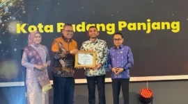Sekdaprov Sumbar, Arry Yuswandi didampingi Ketua KI Sumbar, Musfi Yendra dan anggota Mona Sisca menyerahkan penghargaan kepada Wakil Wali Kota Padang Panjang, Allex Saputra, Selasa (18/11/2025) malam. (Foto: Kominfo Padang Panjang)