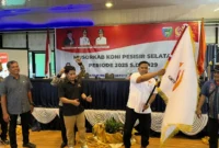 Ketua Umum KONI Pessel terpilih, M Adli mengibarkan bendera KONI, setelah dilakukan penyerahan oleh Ketua Umum KONI Sumbar, Hamdanus. (Foto: Dok. Ky)