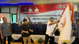 Ketua Umum KONI Pessel terpilih, M Adli mengibarkan bendera KONI, setelah dilakukan penyerahan oleh Ketua Umum KONI Sumbar, Hamdanus. (Foto: Dok. Ky)