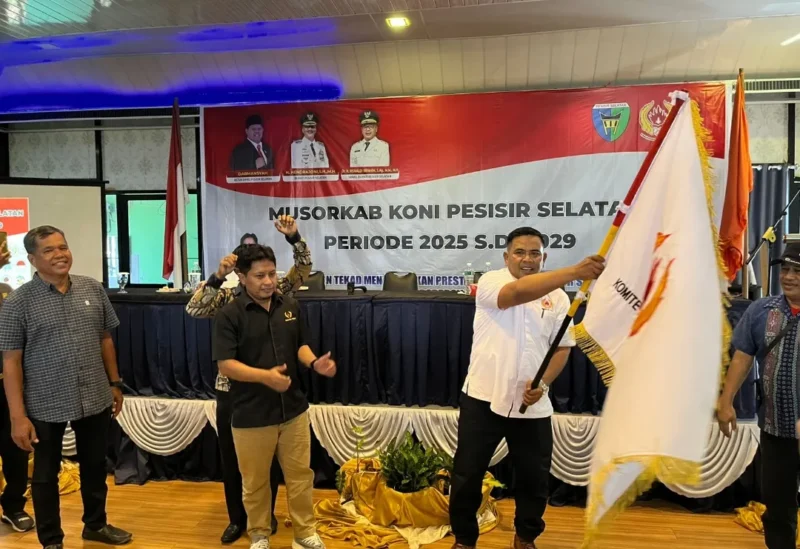 Ketua Umum KONI Pessel terpilih, M Adli mengibarkan bendera KONI, setelah dilakukan penyerahan oleh Ketua Umum KONI Sumbar, Hamdanus. (Foto: Dok. Ky)