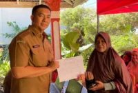 Kepala Disdukcapil Padang Teddy Antonius menyerahkan dokumen kependudukan kepada warga terdampak banjir. (Foto: FB Diskominfo Padang)