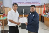Spesialis Kebencanaan Human Initiative Pusat, Jumarsono menyerahkan bantuan kepada Sekdakab Agam, Dr Muhammad Lutfi AR. (Foto: AMC)
