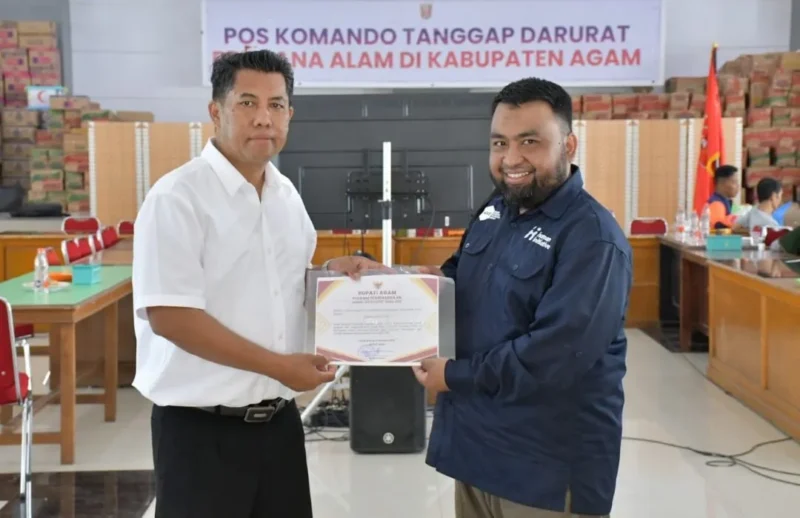 Spesialis Kebencanaan Human Initiative Pusat, Jumarsono menyerahkan bantuan kepada Sekdakab Agam, Dr Muhammad Lutfi AR. (Foto: AMC)