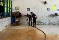 Petugas Damkar Padang membersihkan lantai sekolah dari sedimen lumpur. (Foto: FB Diskominfo Padang)