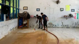 Petugas Damkar Padang membersihkan lantai sekolah dari sedimen lumpur. (Foto: FB Diskominfo Padang)