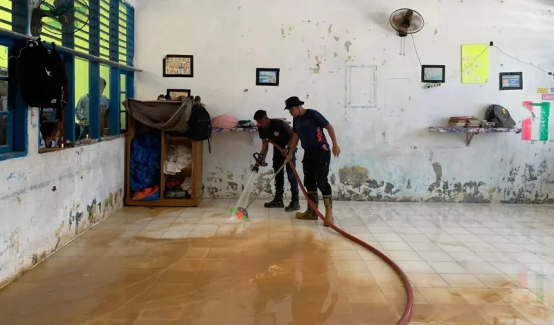 Petugas Damkar Padang membersihkan lantai sekolah dari sedimen lumpur. (Foto: FB Diskominfo Padang)