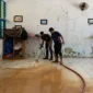 Petugas Damkar Padang membersihkan lantai sekolah dari sedimen lumpur. (Foto: FB Diskominfo Padang)