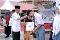 Wakil Bupati Solok Selatan H. Yulian Efi menyerahkan secara simbolis baju seragam gratis kepada siswa. (Foto: Humas Pemkab Solsel)