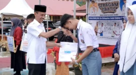 Wakil Bupati Solok Selatan H. Yulian Efi menyerahkan secara simbolis baju seragam gratis kepada siswa. (Foto: Humas Pemkab Solsel)