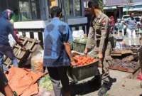 Personel Satpol PP Padang membantu memindahkan barang dagangan PKL yang menghalangi akses jalan di kawasan pasar. (Foto: Humas Satpol PP Padang)