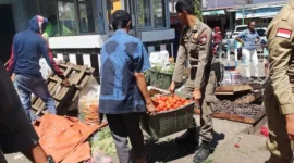 Personel Satpol PP Padang membantu memindahkan barang dagangan PKL yang menghalangi akses jalan di kawasan pasar. (Foto: Humas Satpol PP Padang)