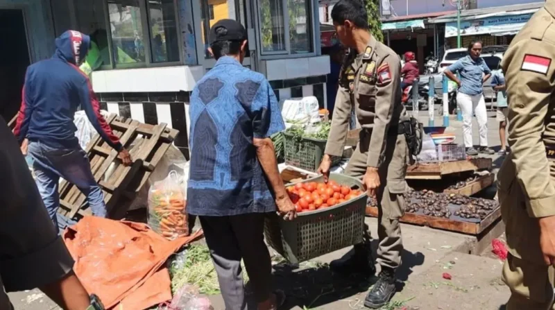 Personel Satpol PP Padang membantu memindahkan barang dagangan PKL yang menghalangi akses jalan di kawasan pasar. (Foto: Humas Satpol PP Padang)