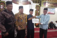 Asisten I Bidang Pemerintahan dan Kesejahteraan Rakyat, Syahrizal Antoni didampingi Ketua DPRD Pessel, Darmansyah menyerahkan bantuan kepada Ketua Pengurus Madjid Al Mukaromah, Zaitul. (Foto: Dok. Niks)