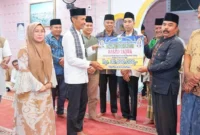 Wakil Bupati Solok Selatan Yulian Efi menyerahkan bantuan saat safari Ramadan Tim II Pemerintah Kabupaten di Masjid Taqwa, Jorong Sawah Siluak, Bomas, Kecamatan Sungai Pagu, Selasa (24/2/2026) malam. (Foto: Diskominfo Solsel)