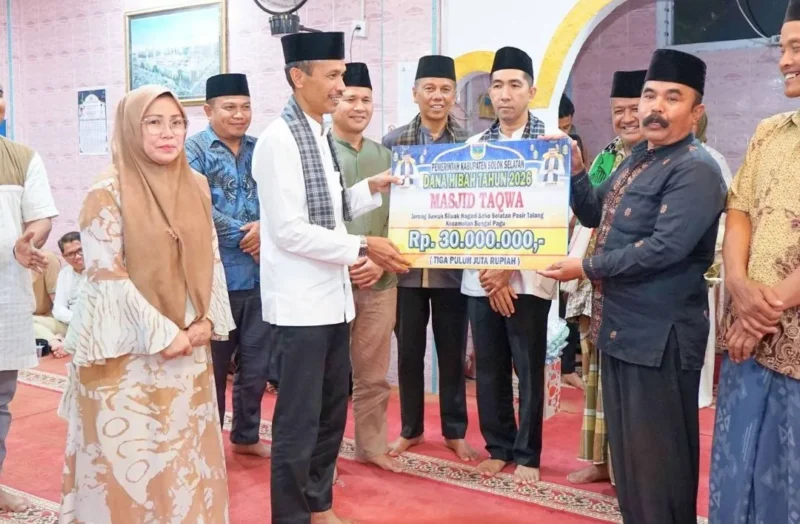 Wakil Bupati Solok Selatan Yulian Efi menyerahkan bantuan saat safari Ramadan Tim II Pemerintah Kabupaten di Masjid Taqwa, Jorong Sawah Siluak, Bomas, Kecamatan Sungai Pagu, Selasa (24/2/2026) malam. (Foto: Diskominfo Solsel)