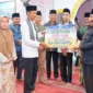 Wakil Bupati Solok Selatan Yulian Efi menyerahkan bantuan saat safari Ramadan Tim II Pemerintah Kabupaten di Masjid Taqwa, Jorong Sawah Siluak, Bomas, Kecamatan Sungai Pagu, Selasa (24/2/2026) malam. (Foto: Diskominfo Solsel)