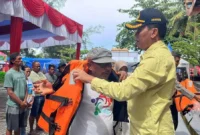 Asisten Pemerintahan dan Kesejahteraan Rakyat Kota Pariaman, Elfis Chandra menyerahkan life jacket kepada pelaku usaha kapal wisata di Panggung Utama Pantai Gandoriah, Minggu (29/3). (Foto: Kominfo Pariaman)