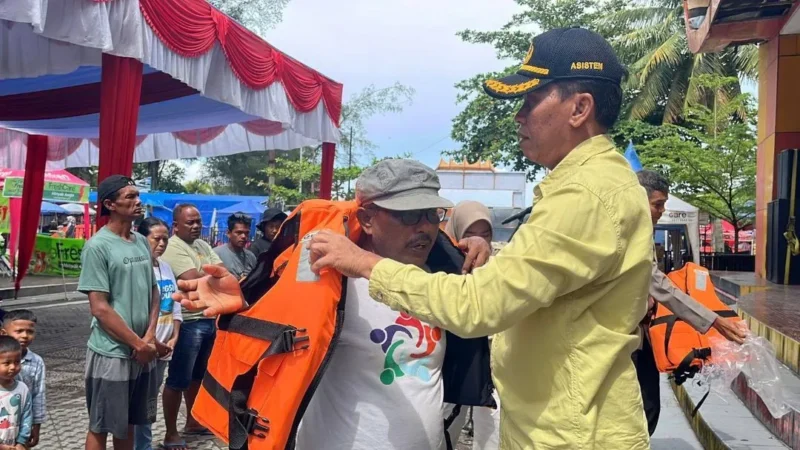 Asisten Pemerintahan dan Kesejahteraan Rakyat Kota Pariaman, Elfis Chandra menyerahkan life jacket kepada pelaku usaha kapal wisata di Panggung Utama Pantai Gandoriah, Minggu (29/3). (Foto: Kominfo Pariaman)