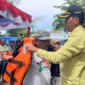 Asisten Pemerintahan dan Kesejahteraan Rakyat Kota Pariaman, Elfis Chandra menyerahkan life jacket kepada pelaku usaha kapal wisata di Panggung Utama Pantai Gandoriah, Minggu (29/3). (Foto: Kominfo Pariaman)