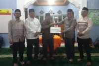 Asisten I Bupati Pessel Syahrizal Antoni menyerahkan bantuan kepada pengurus Masjid Nurul Iman saat kunjungan Safari Ramadhan di Kampung Rangeh, Nagari Kambang Barat. (Foto: Dok. Niks)
