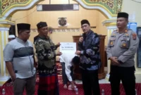 Bupati Pessel, Hendrajoni saat menyerahkan bantuan untuk pembangunan Masjid Thoiyibah, kepada ketua pengurus Masjid, Syahrial. (Foto: Dok. Niks)