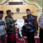 Bupati Pessel, Hendrajoni saat menyerahkan bantuan untuk pembangunan Masjid Thoiyibah, kepada ketua pengurus Masjid, Syahrial. (Foto: Dok. Niks)