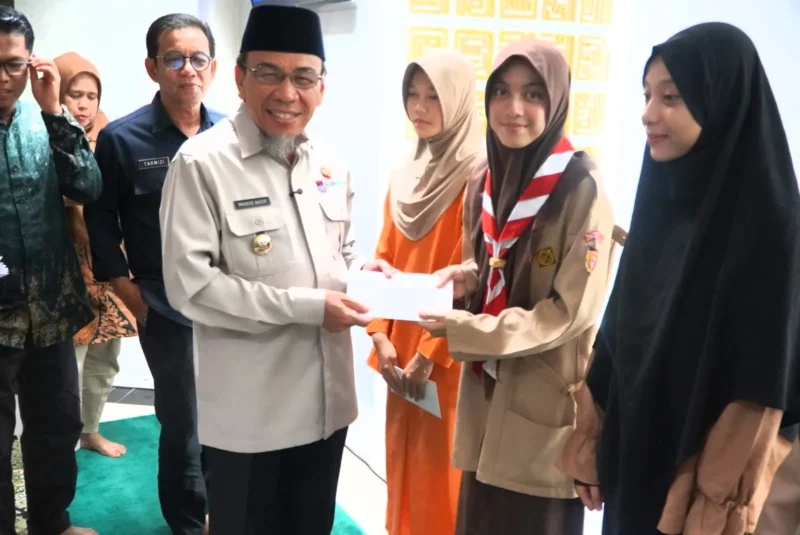 Wakil Wali Kota Padang, Maigus Nasir menyerahkan santunan kepada anak yatim dan piatu binaan Masjid Ukhuwah Balai Kota Padang, Aia Pacah, Kamis (12/3/2026). (Foto: Prokopim Padang)